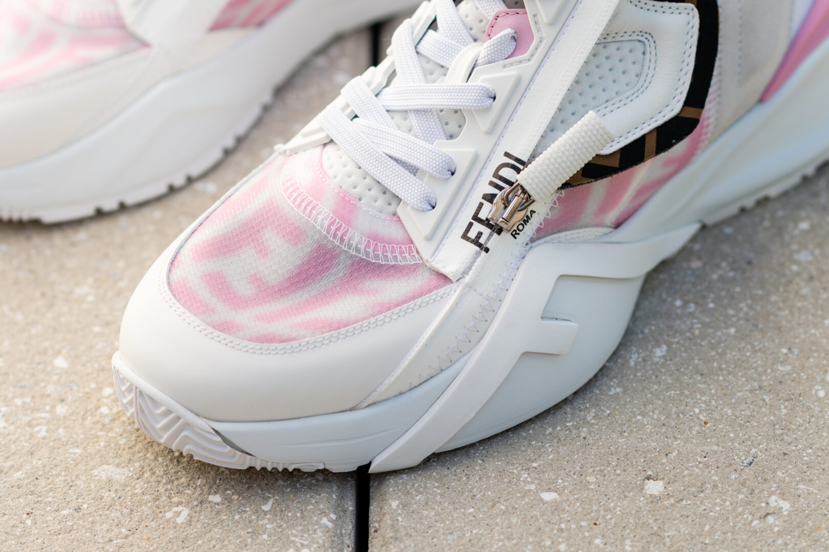 A pair of white and pink sneakers on the ground.