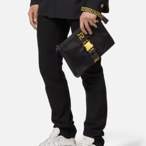 A person holding versace greca pouch bag