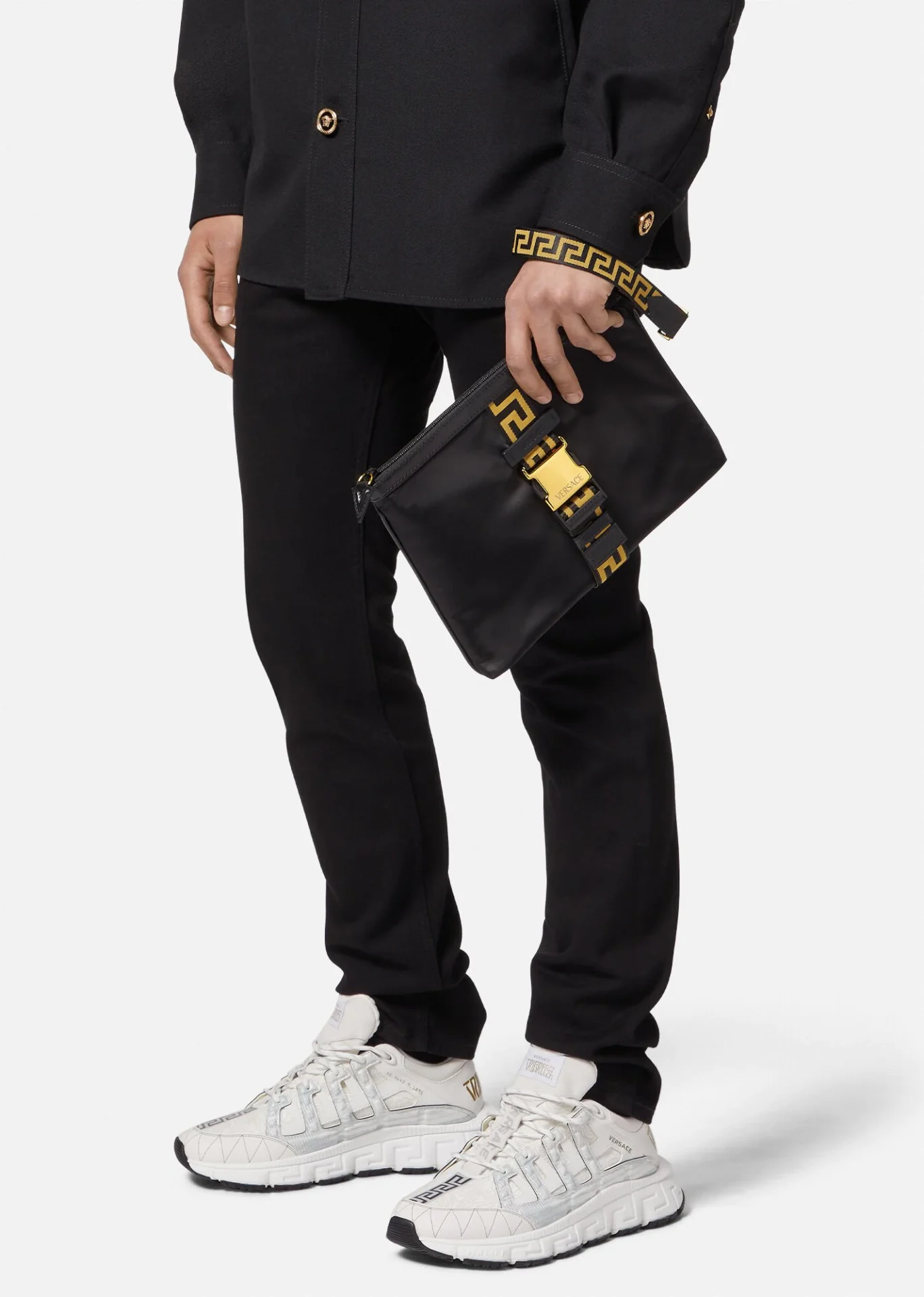 A person holding versace greca pouch bag