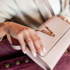 A person holding a pink virtus calf leather clutch