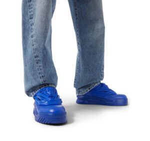 A person wearing a pair of jeans and blue shoes