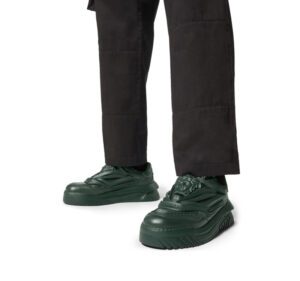 A person wearing black pants and dark green shoes